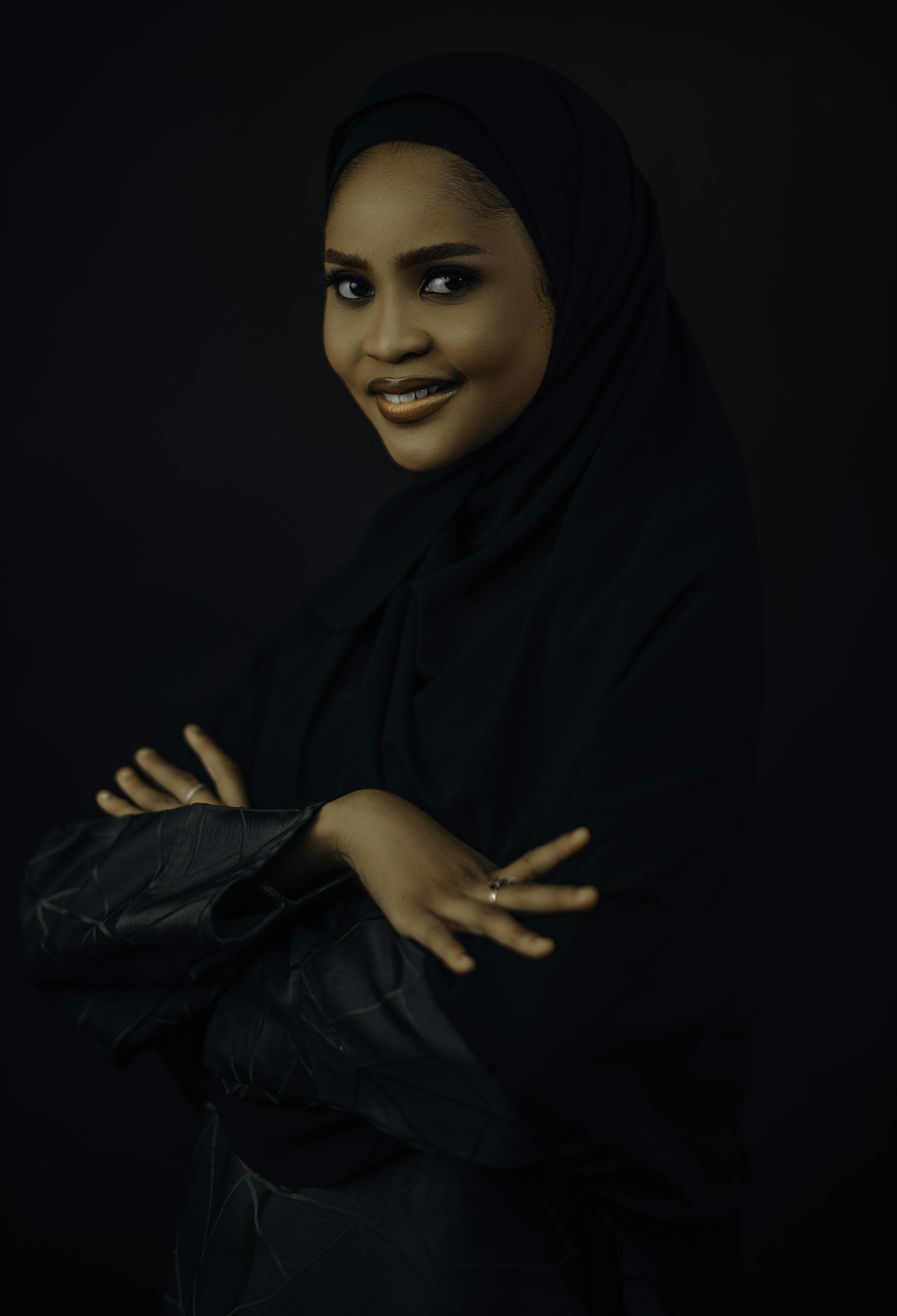 Studio portrait of a smiling woman wearing a hijab, exuding confidence and elegance.